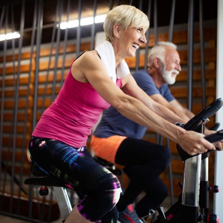 Happy mature people doing indoor biking in a fitness club